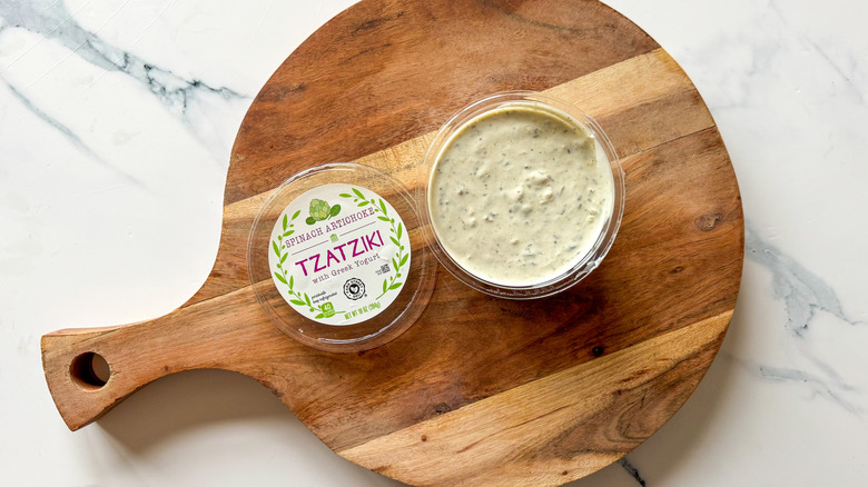 Spinach Artichoke Tzatziki dip on round, wooden cutting board