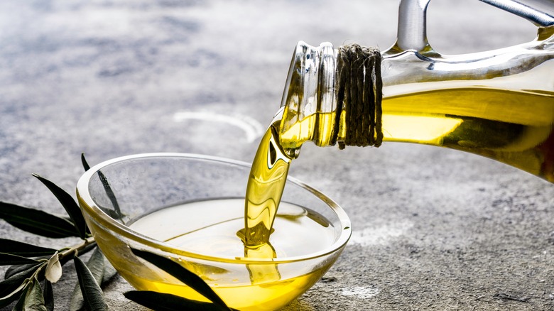 Bottle of olive oil being poured into bowl