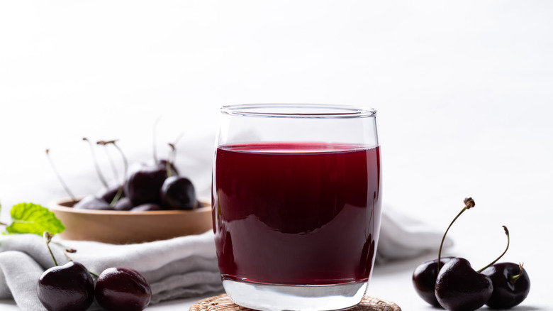 Fresh cherry juice in glass with whole cherries nearby
