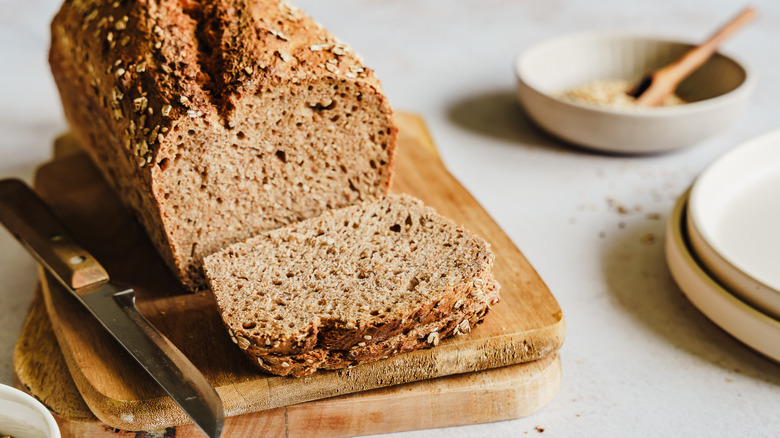 Artisanal loaf of whole grain bread sliced on cutting board