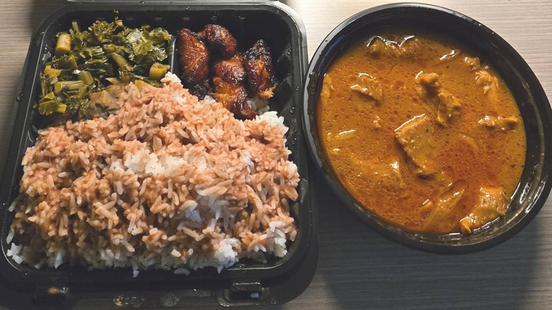 A takeout tray with greens, plantains, rice and a bowl with meat and juices