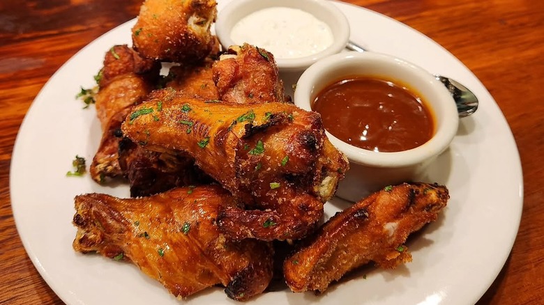 Mustard's Crazy Good Smoked Chicken Wings on a plate with two dipping sauces
