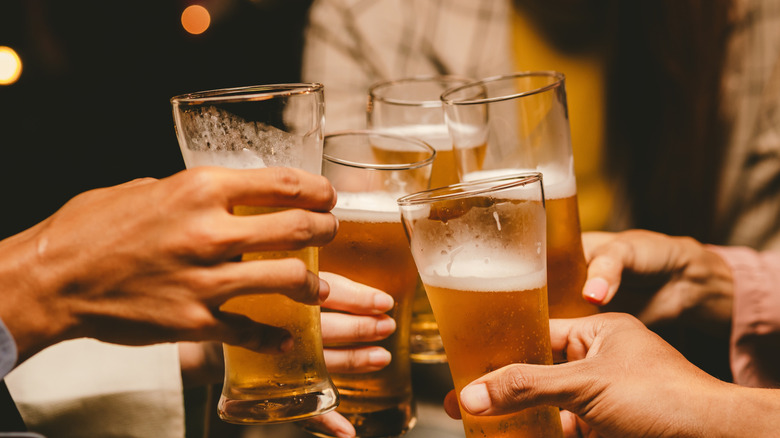 A group of people clinking glasses full of beer