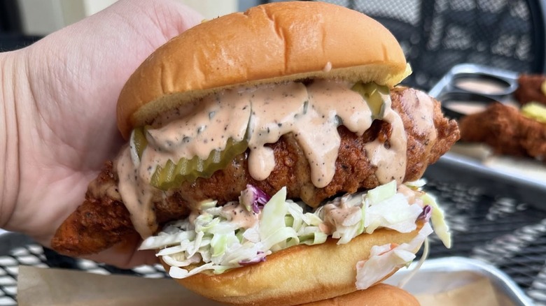 Someone holding the Slaw Slider hot chicken sandwich from Main Bird