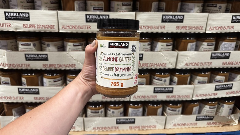 Hand holding a jar of almond butter at Costco