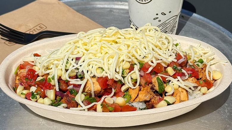 A burrito bowl with chicken topped with cheese at Chipotle