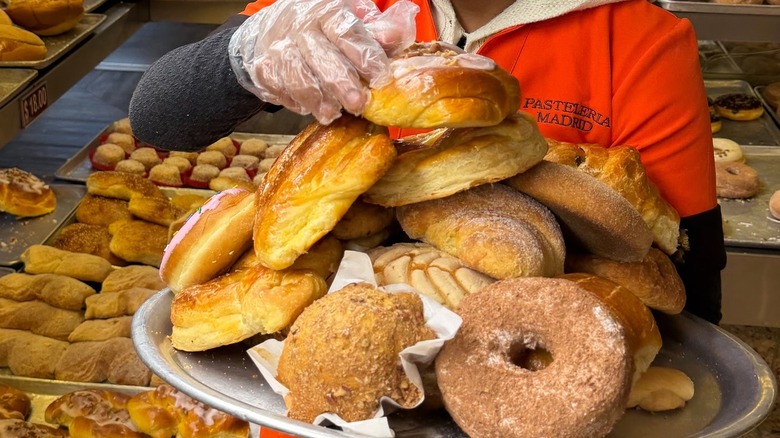 A woman loading a tray of sweet breads at Pasteleria Madrid.