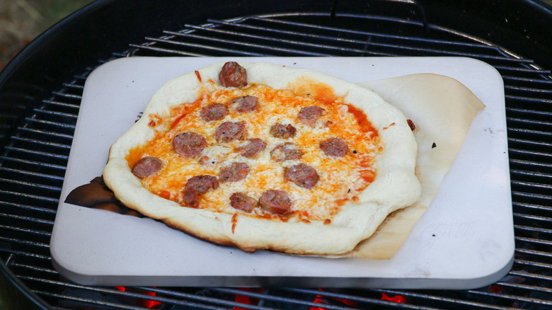 Cooking sausage pizza on a pizza stone with a grill