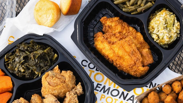 Black plastic to-go containers filled with soul food