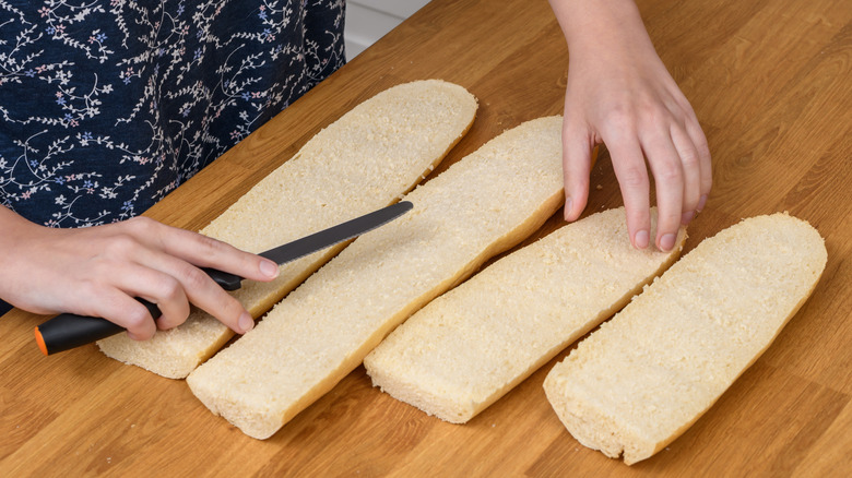 Person cutting Italian bread for sandwich