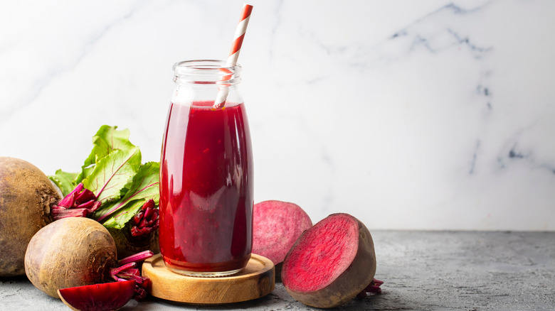 beet juice in a bottle with cut beets on table.