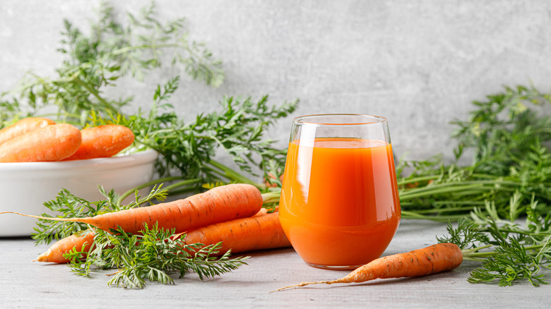 carrot juice in a glass on a table with fresh carrots