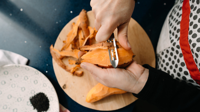 close up of person's hands peeling a sweet potato