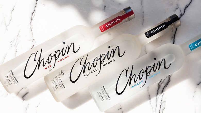 There bottles of Chopin vodka lined up at an angle on a marble surface