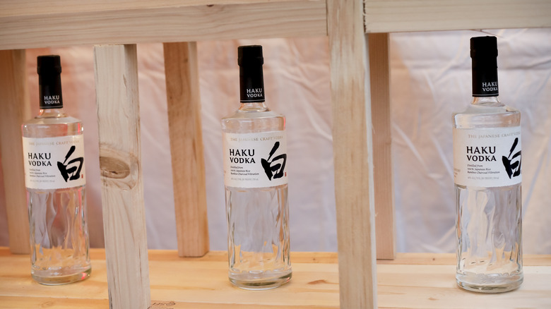 Three bottles of Haku vodka displayed in a wooden shelf
