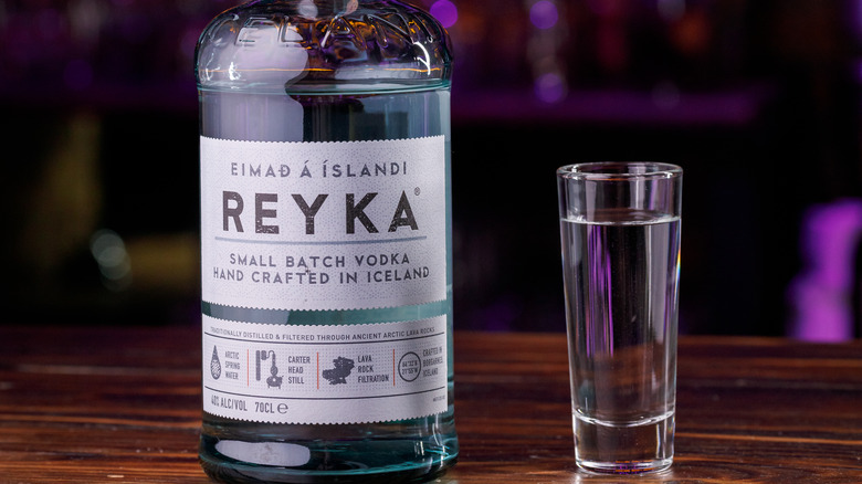 A closeup of Reyna's vodka bottle next to a shot glass