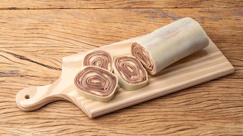 Bolo de rolo, showing both the log and its slices, on a wooden serving board