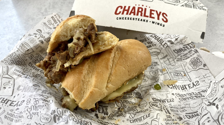 The Philly Cheesesteak from Charleys cut in half on top of the take-out packaging.