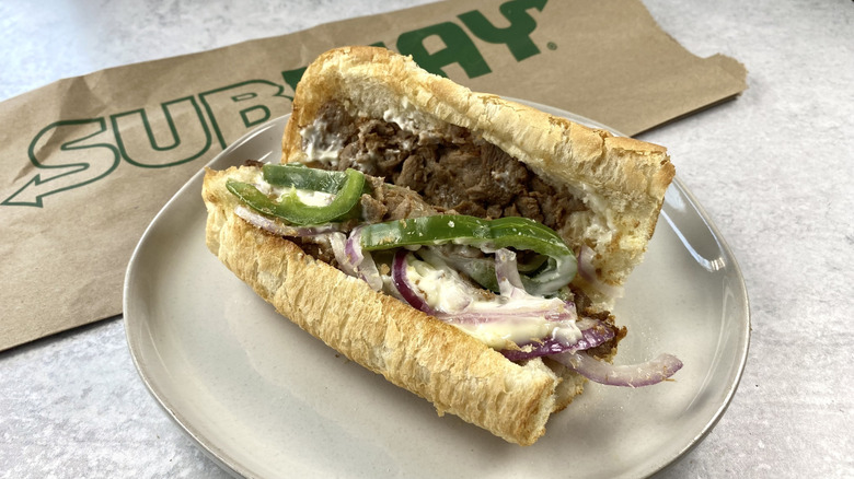 Subway's The Philly sandwich on a plate next to the packaging.