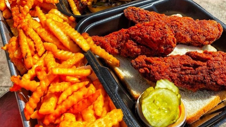 A takeout container of chicken tenders, fries, and pickles from Dave's Hot Chicken