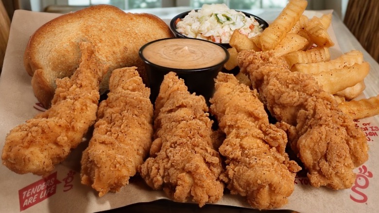 A plate of chicken tenders, fries, Texas toast, coleslaw, and sauce from Huey Magoo's