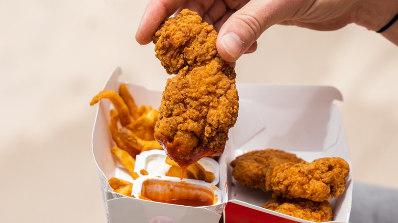 A person holding a Chicken Strip from Jack in the Box