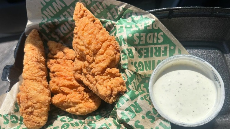 A takeout container of chicken fingers with ranch dressing from Wingstop