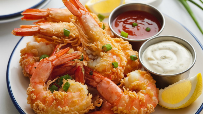 A plate of fried shrimp with dipping sauces