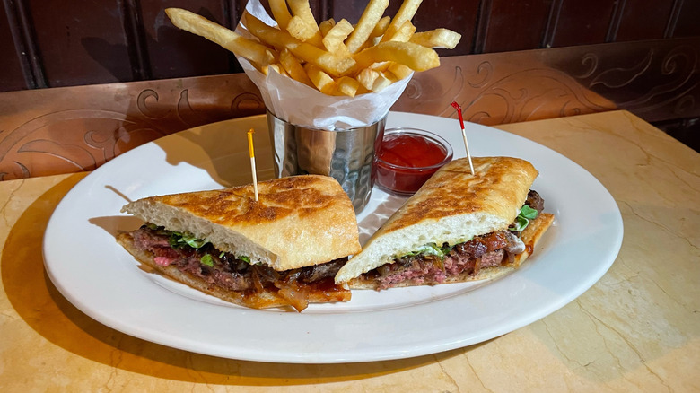 The crosscut of the Bistro Burger on a white plate with a side of fries