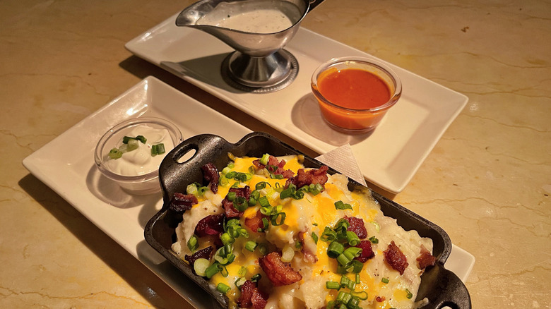 A side of loaded potatoes, sour cream, ranch, and hot sauce