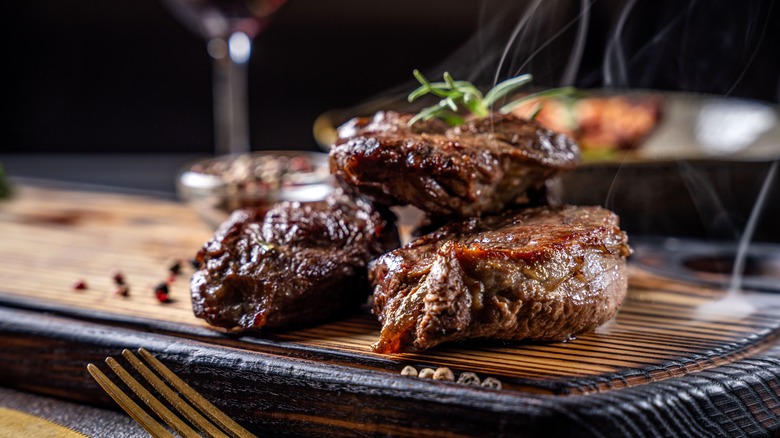 A plate of juicy, steaming steaks topped with rosemary sprigs