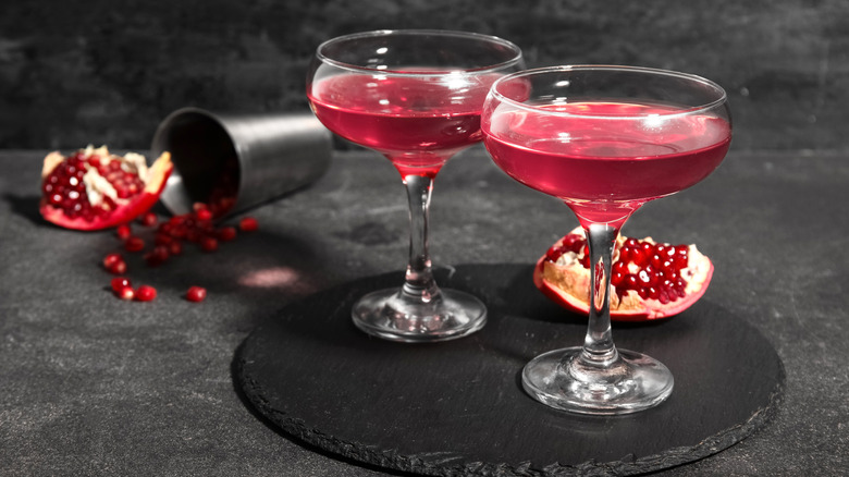 Pomegranate Cosmopolitan with fresh pomegranate and cocktail shaker on a dark background