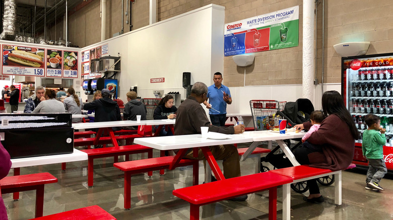 Customers sit at Costco food court picnic tables to eat