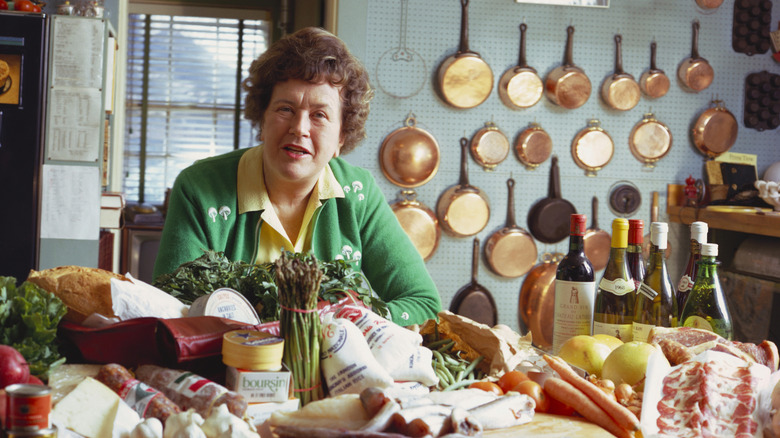 Chef Julia Child sits in her kitchen behind cooking ingredients