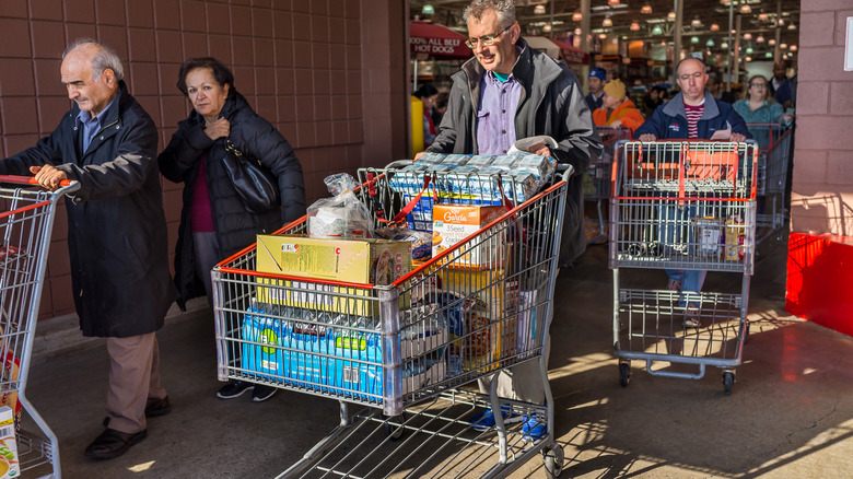 people with shopping carts filled with groceries walking out of Costco