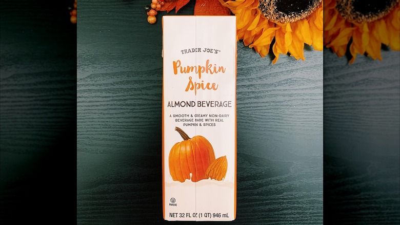 Trader Joe's Pumpkin Spice Almond Beverage on a dark wood surface with faux flowers