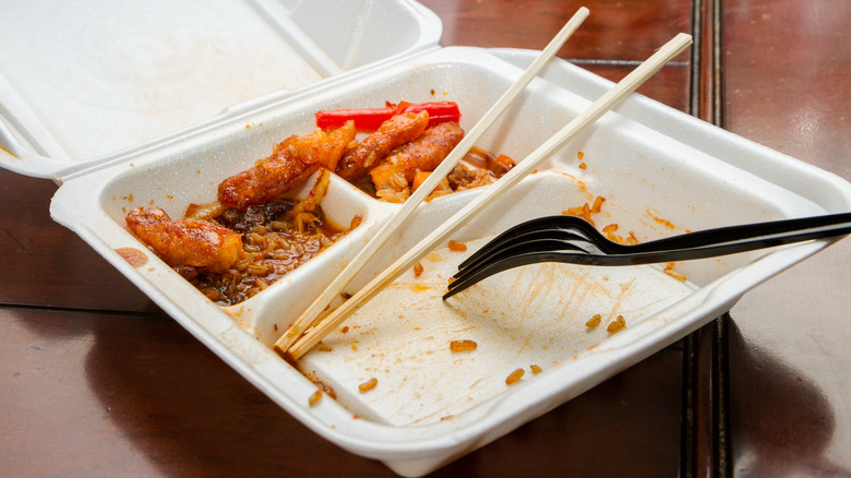 Leftover Chinese takeout in container with both a fork and chopsticks