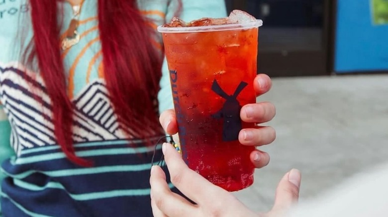 A woman handing her friend a Dutch Bros Vampire Slayer drink