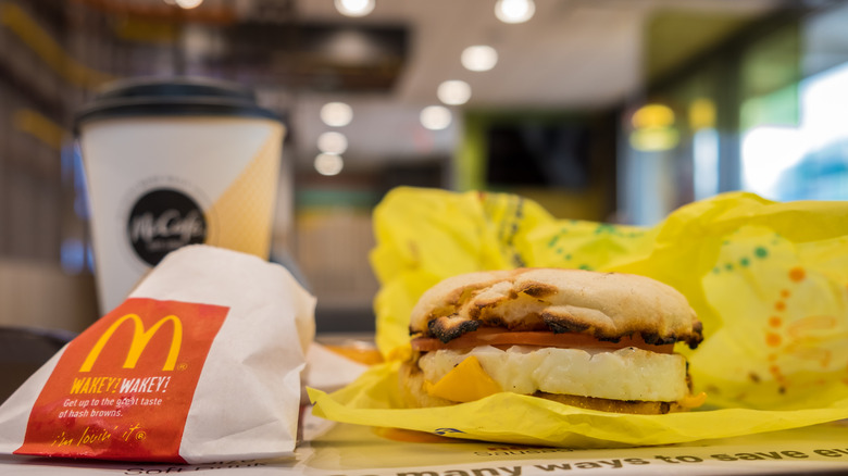 An Egg McMuffin is on a tray next to McDonald's Hash Browns and coffee