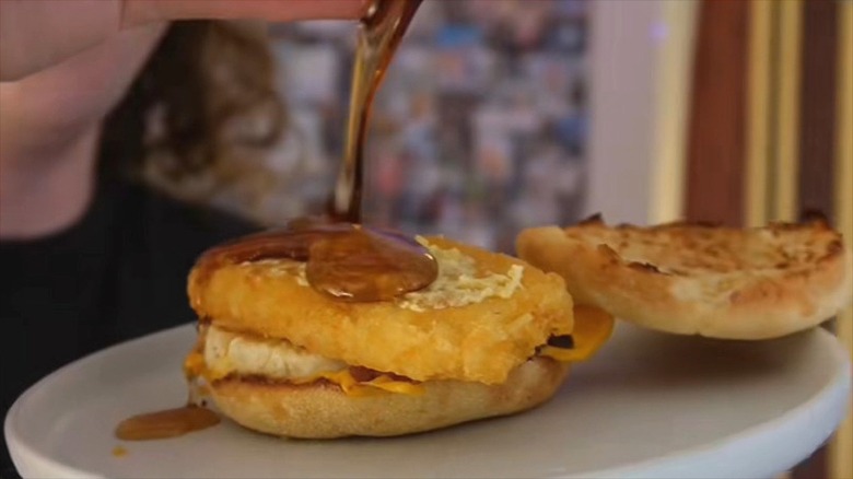 Maple syrup is poured onto an Egg McMuffin topped with a McDonald's Hash Brown