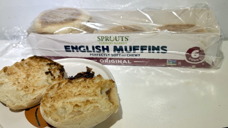 A package of Sprouts Original English Muffins behind a plate with a toasted muffin on it