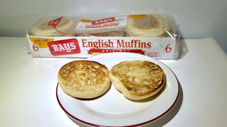 A package of Bays Original English Muffins behind a plate with a toasted muffin on it