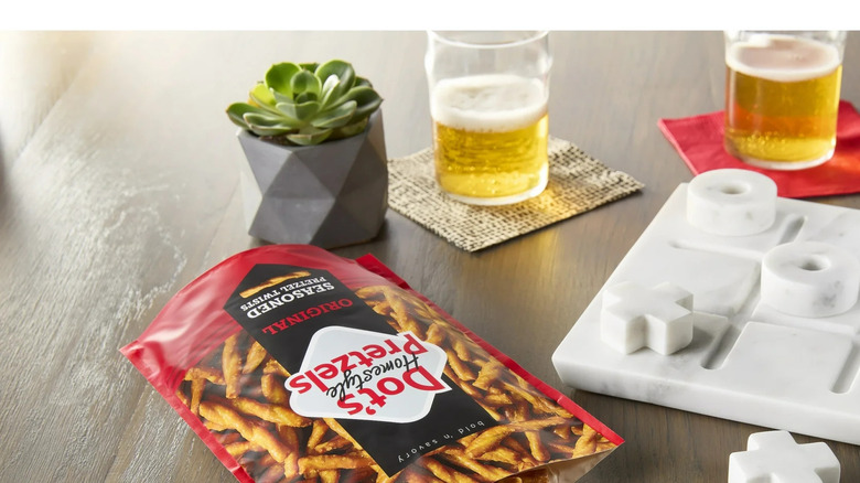 A bag of Dots on its side on a table alongside a game of tic-tac-toe and two beers