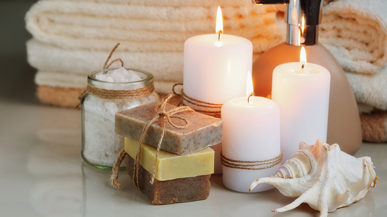Modern day soaps and candles on a countertop next to a sea shell