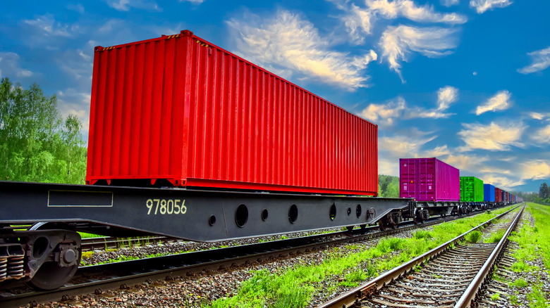 Train cars traveling down a track with blue sky overhead