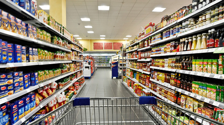 edge of grocery cart in a supermarket aisle lined with products
