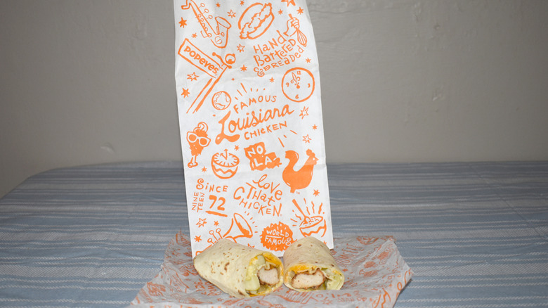 Classic Blackened Chicken Wrap in front of Popeyes to-go bag