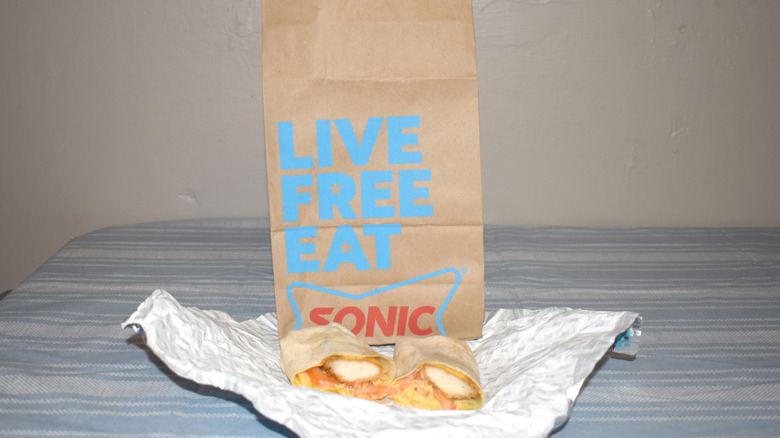 Cheesy Baja Crispy Tender Wrap in front of Sonic to-go bag