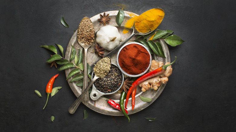 Various spices, herbs, and chiles on a silver plate