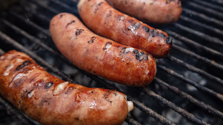 A close up of four grilled hot dogs on grill grates